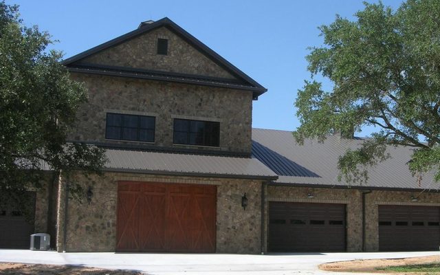 Stone barndominium with shop bays and upstairs living space, built by Cross Creek Construction