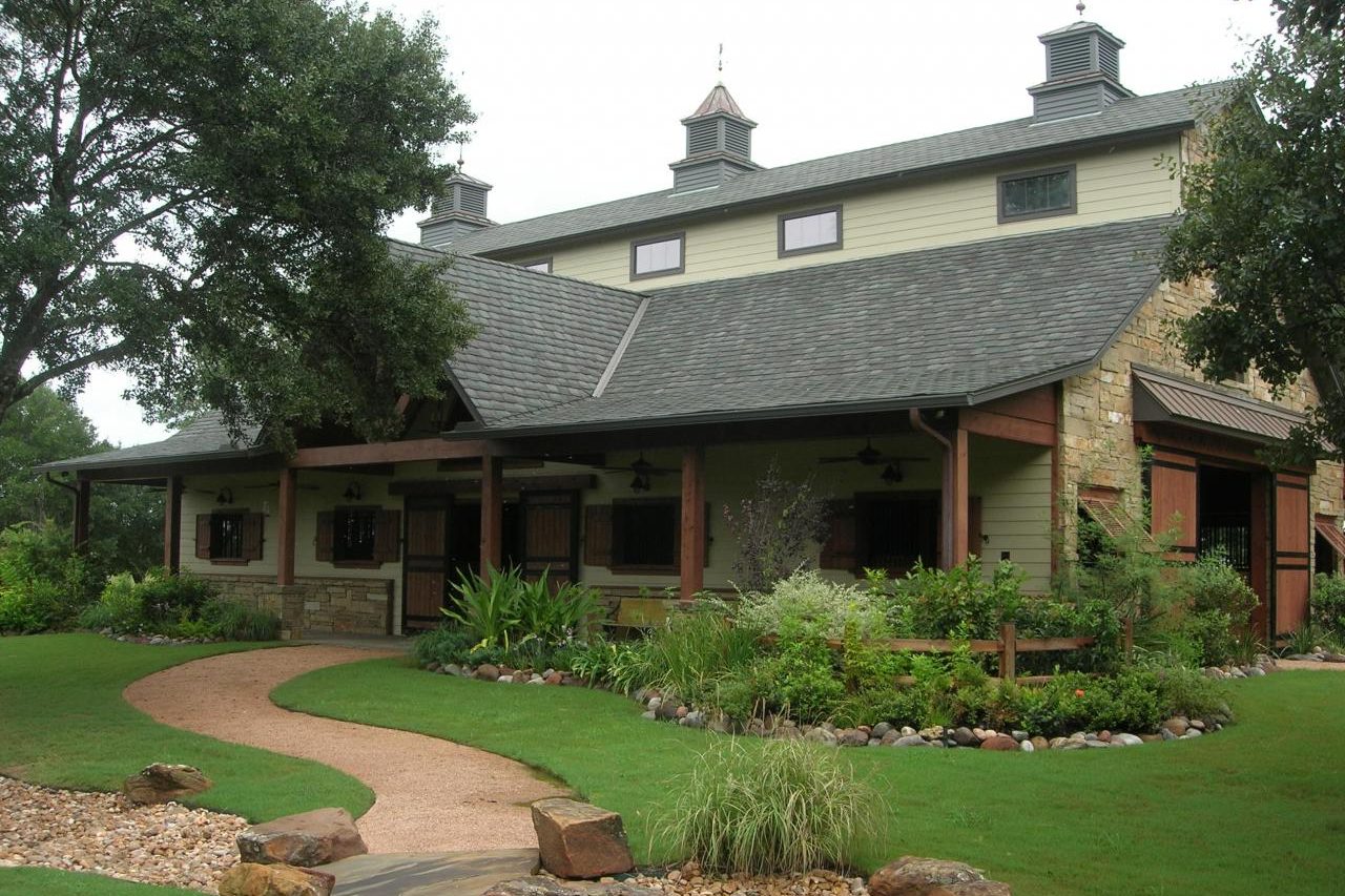 Cypress Stable stone and cedar horse barn with landscaped path